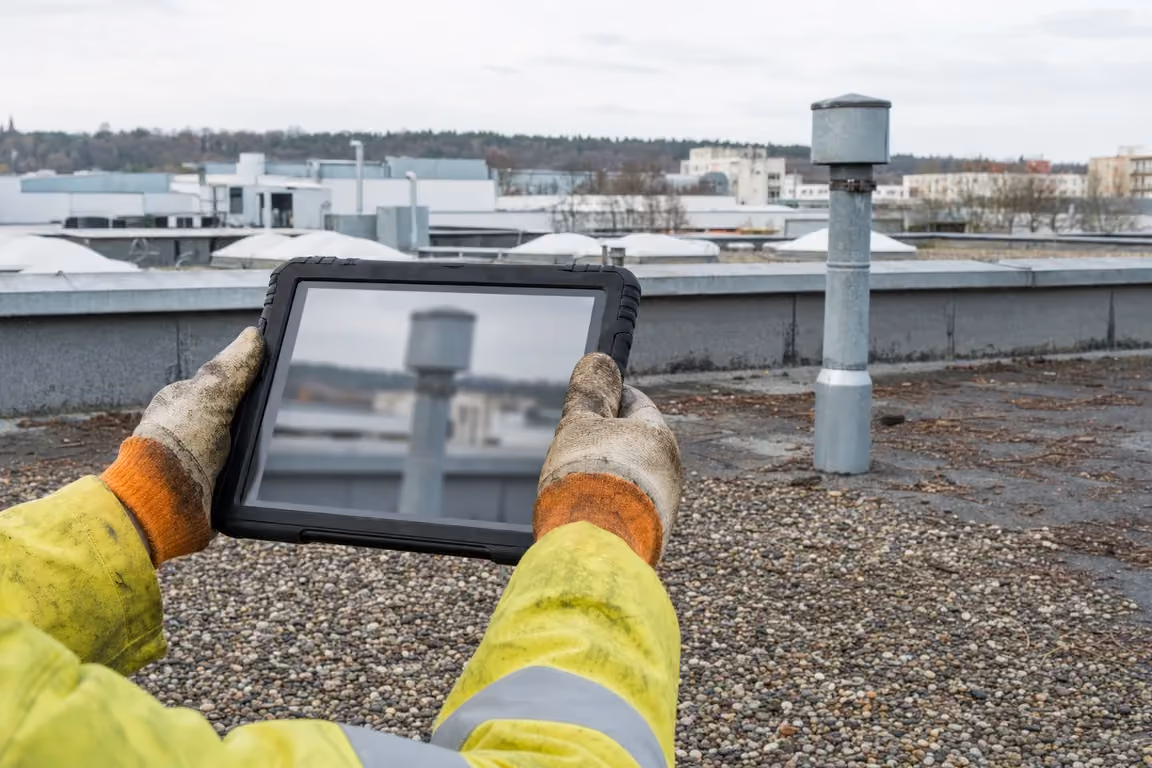Techniker dokumentiert einen Entlüfter mit dem Tablet: die Wartungsakte, an der sich die Wirtschaftlichkeit der Dachwartung ablesen lässt